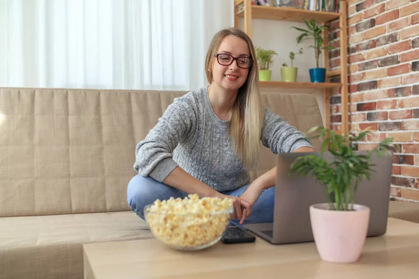 Žena sedí na pohovce v obývacím pokoji a sleduje seriál s popcornem — Stock fotografie
