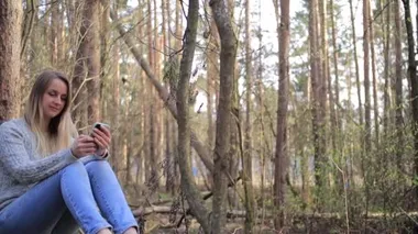 Bahar ormanında akıllı telefondan konuşan bir kadın.