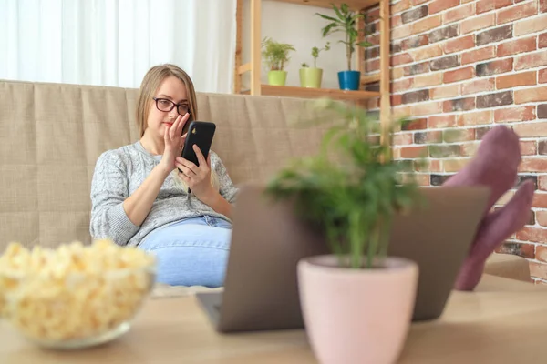 Giovane donna seduta sul divano in soggiorno e fare shopping da smartphone — Foto Stock