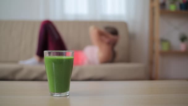 Vidro de smoothie verde com mulher desfocada tentando perder peso no fundo — Vídeo de Stock
