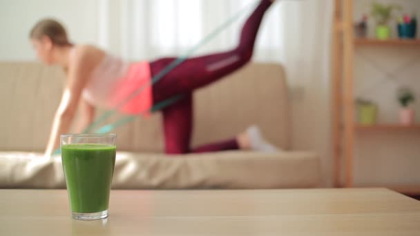 Склянка зеленої смуги з розмитою жінкою, яка намагається схуднути на фоні — стокове відео
