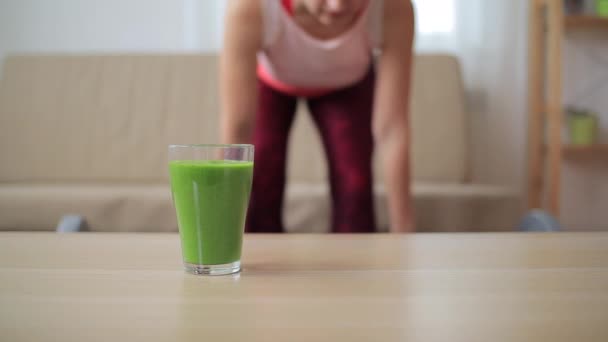 Egy pohár zöld smoothie elmosódott nő próbál lefogy a háttérben — Stock videók