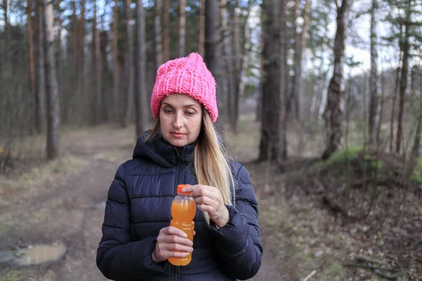 Женщина с бутылкой апельсинового сока или смузи в парке — стоковое фото