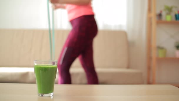 Vidro de smoothie verde com mulher desfocada tentando perder peso no fundo — Vídeo de Stock