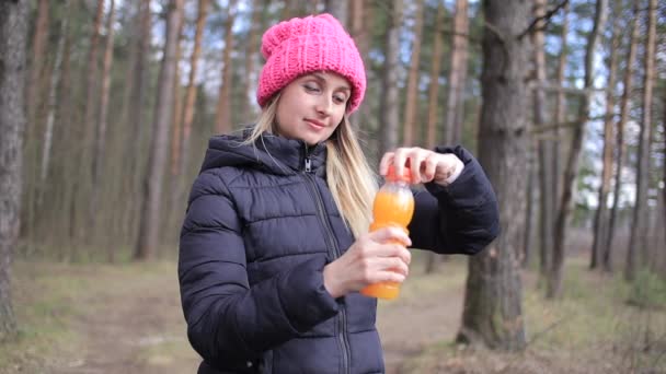 Женщина с бутылкой апельсинового сока или смузи в парке — стоковое видео