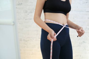 Genç kız aynanın yanında ölçü almaya çalışıyor.