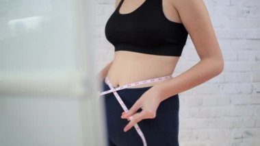 Genç kız aynanın yanında ölçü almaya çalışıyor.