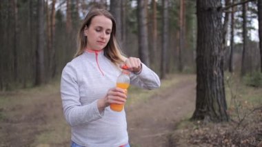 Parkta güneşli bir günde portakallı smoothie ile sportif bir kadın.