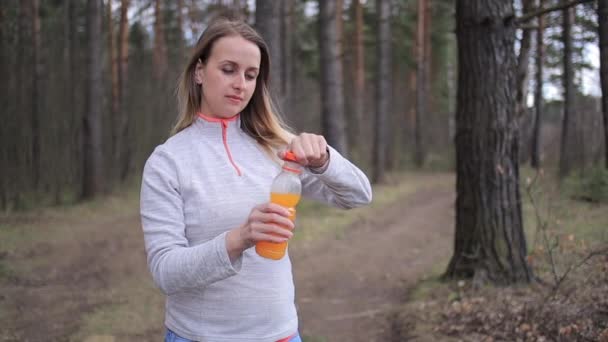 Mujer deportiva con batido de naranja en el día soleado en el parque — Vídeos de Stock