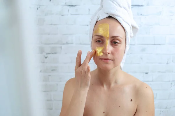 Vrouw die gouden hydrogel masker op gezicht aanbrengt — Stockfoto