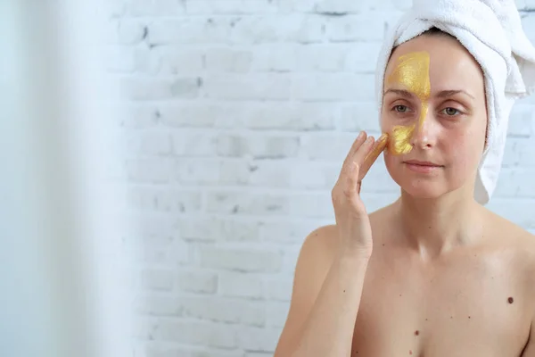 Vrouw die gouden hydrogel masker op gezicht aanbrengt — Stockfoto