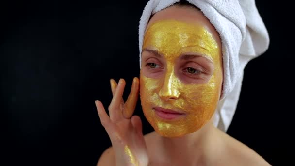 Woman applying golden hydrogel mask on face — Stock Video