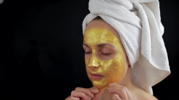 Žena odstraňuje zlatý hydrogel masku na tváři — Stock video