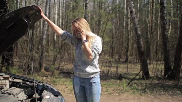 Молодая женщина рядом со сломанной машиной говорит по телефону — стоковое видео