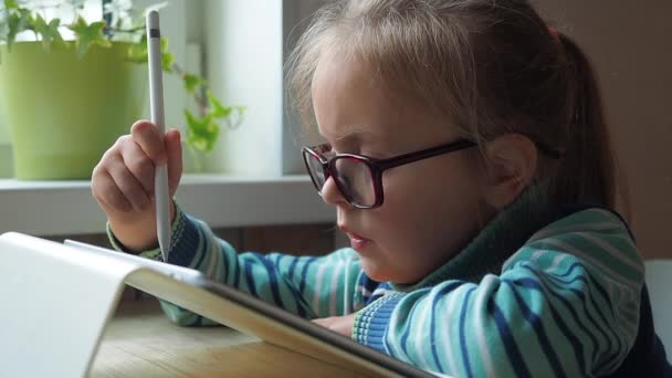 Маленька дівчинка з планшетом і стилусом навчається малювати онлайн — стокове відео