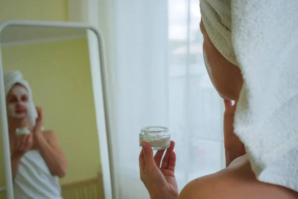 Mujer después del baño aplicando máscara de spa en su cara —  Fotos de Stock