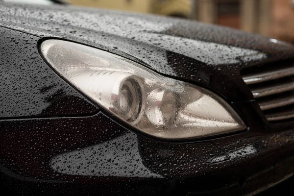 Modern car headlights with water drops. — Stock Photo, Image