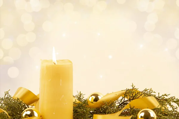 Espace de copie de Noël avec une bougie jaune allumée, des branches de pin, un ruban de satin doré et des boules de Noël dorées sur un fond à motifs clairs — Photo