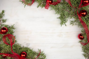 Çam dalları, kırmızı organza kurdelesi ve parlak ahşap arka planda kırmızı Noel mücevherleri olan noel fotokopi alanı