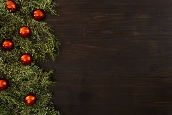 Mieszkanie leżał przestrzeni Christmas kopia z gałęzi sosny i czerwone bombki świąteczne na stronie na ciemnym drewnianym tle — Zdjęcie stockowe