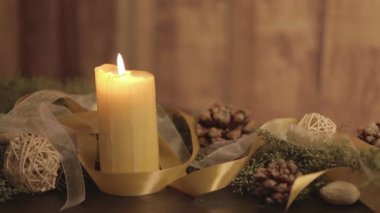 Hareketli mum alevleri, çam dalları, doğal çam kozalakları, altın saten ve beyaz organza süslemeleri olan bir Noel ortamını kapatın. 