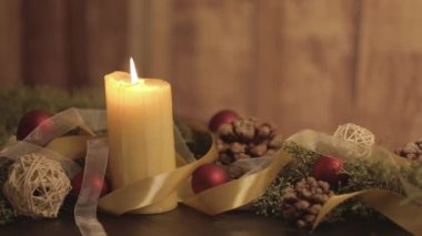 Hareketli mum alevleri, çam dalları, doğal çam kozalakları, kırmızı mücevherler, altın saten ve beyaz organza kurdeleleri olan bir Noel ortamını kapatın.