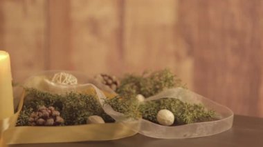 Hareketli bir mum alevleri, çam dalları, doğal kozalaklar, kırmızı mücevherler, altın saten ve beyaz organza kurdeleleri ile donatılmış bir Noel ortamını kapatın.