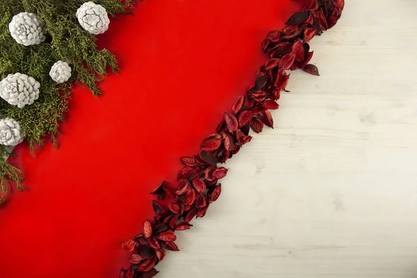 Flach liegender roter Weihnachtskopierraum mit diagonalem roten Streifen auf hellem Holzgrund, Tannenzapfen, weißen Tannenzapfen und roten Blütenblättern — Stockfoto