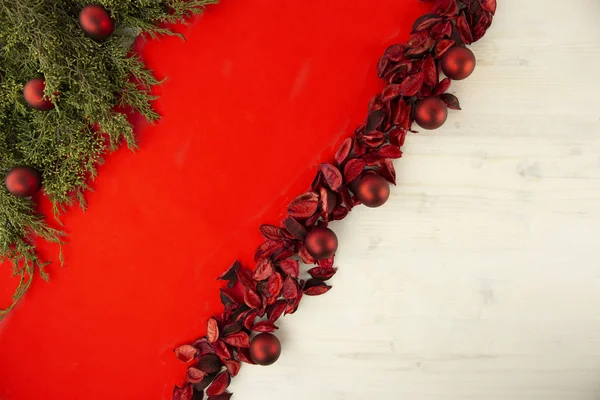 Flach liegender roter Weihnachtskopierraum mit diagonalem roten Streifen auf hellem Holzgrund, Tannenzweigen, roten Blütenblättern und roten Christbaumkugeln — Stockfoto