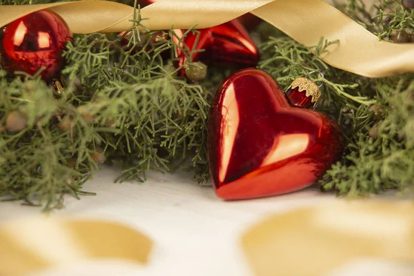 Close up of a Christmas red baubles with earth shape with around pine branches, red baubles and satin gold ribbon on wooden background with bokeh effect — Stock Photo, Image