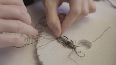 Yaşam tarzı konsepti, hayatınızı yeniden keşfetmek için evden çalışmak: ön planda renkli iplik makaraları ve düz renkli bokeh efektiyle çekilmiş makrome düğümlü mücevherler yapan kadın ellerinin yakın plan detayı