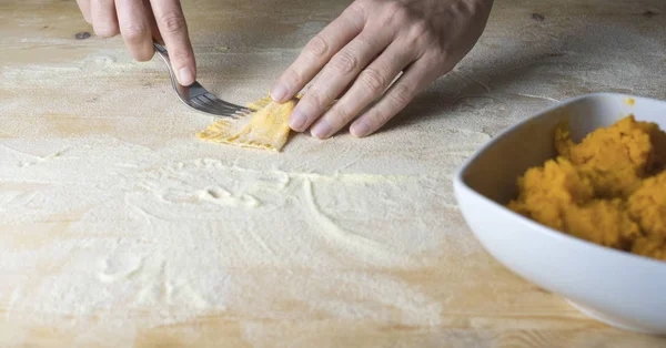 Närbild process gör ravioli vegan hemlagad pasta. Hemmafru kock stänger med en gaffel "tortelli di zucca", traditionell italiensk pasta, kvinna matlagning mat på kök — Stockfoto