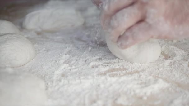 白い小麦粉と軽い木製のテーブルの上に自宅でピザ生地を混練男性の手のクローズアップ — ストック動画