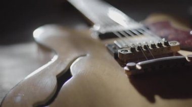 Pirinç kaplama mekanik ile hafif ahşap yapılmış eski bir yarı akustik gövde gitarının yakın çekim görüntüsü ve şimdi zaman tarafından mahvedilmiş düşük güneş ışığı oyunları - Pro res logaritması