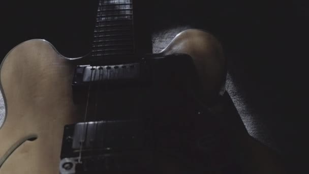 浅色木料中的一把旧的半声学空心弹奏吉他的特写镜头 其反射的是低阳 在暮色中发出光芒 — 图库视频影像