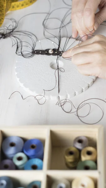 Lifestyle concept, work from home to reinvent your life: close-up of woman hands making macrame knotted jewelry with stone beads and tools on light wooden table — Stock Photo, Image