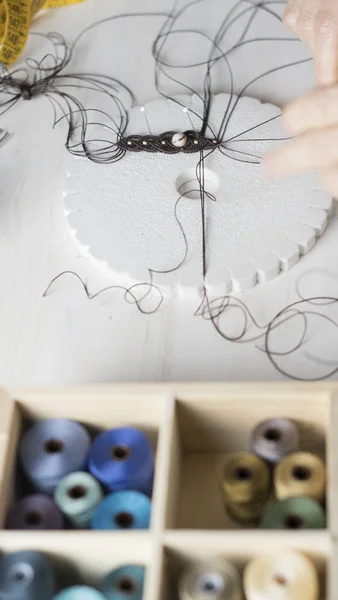 Lifestyle concept, work from home to reinvent your life: close-up of woman hands making macrame knotted jewelry with stone beads and tools on light wooden table — Stock Photo, Image