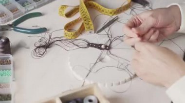 Yaşam tarzı konsepti, hayatınızı yeniden keşfetmek için evden çalışmak: kadın ellerine yakın plan taş boncuklar ve açık ahşap masa üzerinde aletler ile makrome düğümlenmiş mücevherler yapmak