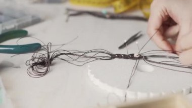 Yaşam tarzı konsepti, hayatınızı yeniden keşfetmek için evden çalışmak: kadın ellerine yakın plan taş boncuklar ve açık ahşap masa üzerinde aletler ile makrome düğümlenmiş mücevherler yapmak