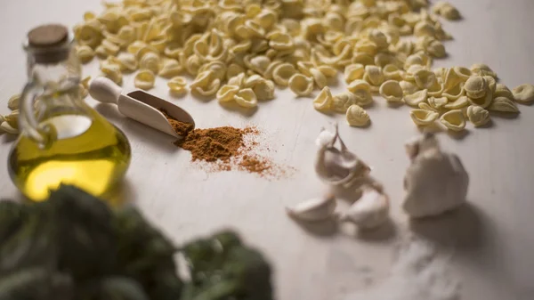 Gros plan de l'orecchiette de pâtes fraîches typiques des Pouilles italiennes sur une table avec brocoli, ail, huile et poudre de piment — Photo