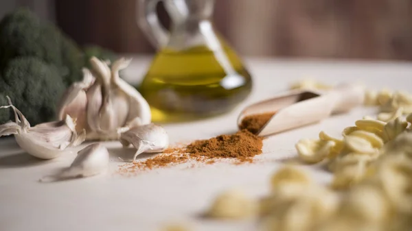 Primo piano delle tipiche orecchiette di pasta fresca pugliese su un tavolo con broccoli, aglio, olio e peperoncino in polvere — Foto Stock