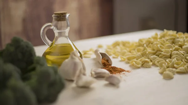 Збільшення типових італійських апулійських свіжих макаронів на столі з броколі, часником, олією та чилі. — стокове фото