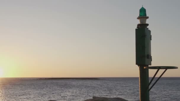 朝阳或日落时的海洋全景 前景是在港口有一个小灯塔 — 图库视频影像