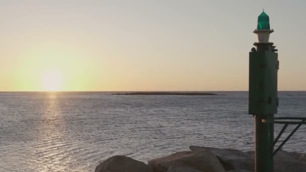 朝阳或日落时的海洋全景 前景是在港口有一个小灯塔 — 图库视频影像