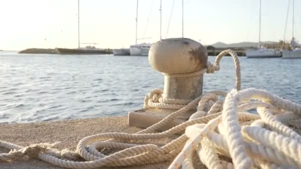 系着绳子 躺在地上 各种船尾在背光下的系泊护柱在日出或日落时的背光前景 — 图库视频影像