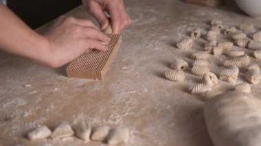 Ev yapımı vejetaryen gnocchi makarnanın tamamını un ile kapatıyoruz. Ev aşçısı hamuru ahşap kesim tahtasına yuvarlar, geleneksel İtalyan makarnası, kadın mutfakta yemek pişirir.