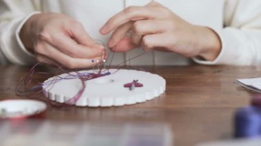 Yaşam tarzı konsepti, hayatınızı yeniden keşfetmek için evden çalışmak: kadın ellerine yakın plan taş boncuklar ve ahşap masadaki aletlerle makrome düğümlü mücevherler yapmak