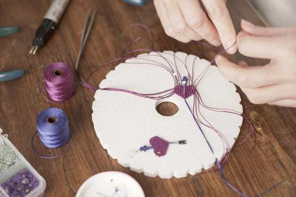 ライフスタイルのコンセプト 家から仕事あなたの人生を再発明する 女性の手のクローズアップマクラメを作ることは 木のテーブルの上に組紐を作成するフクシア糸を結びます — ストック写真
