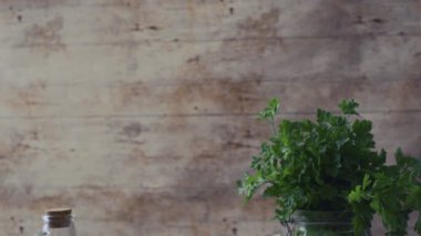 Tipik İtalyan spagetti aglio olio e peperoncino (sarımsak, yağ ve acı biber) malzemelerinin baştan aşağı yakından incelenmesi ve ahşap masa üzerinde maydanoz dalları bulunan cam bir kavanoz.