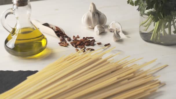 典型的なイタリア料理のスパゲッティ アリオ オリオ ペペロンチーノ ニンニク オイル 唐辛子 材料の上から下まで 軽い木製のテーブルの上にパセリの小枝とガラス瓶 — ストック動画